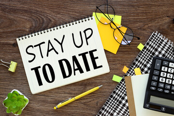 Stay Up To Date. text. Notepad, white sticker and pensil on the desk.