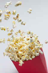 Popcorn popping into the air from a red paper bowl.