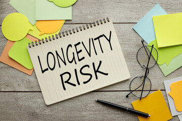 LONGEVITY RISK. a lot of stickers are scattered on a wooden background with text on a notepad