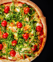 Traditional italian pizza with cherry tomatoes on a dark background.