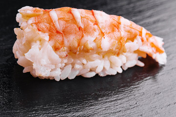 Sushi shrimp and rice on a black wood