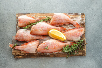 Fresh red snapper with lemon, rosemary, salt on a wooden board. banner, menu, recipe place for text, top view