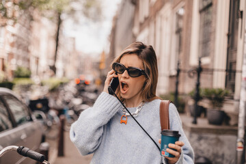 Shocked anxious young woman receiving offending news over her cell phone. Shocked surprised woman...
