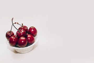 Ripe red cherries in white plates on the table.