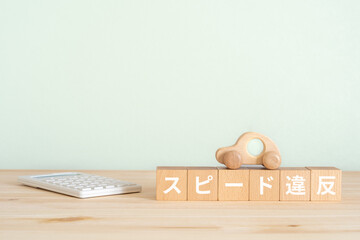 スピード違反と書かれたブロックと電卓と車のおもちゃ