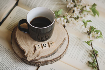book and a cup of coffee with spring twig blooming and word joy