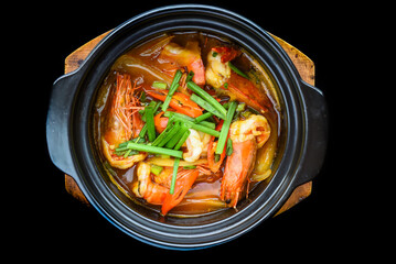 Shrimps with vegetables in bouillon isolated on black background top view