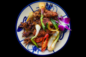 Fried squid with vegetables on black background for a menu