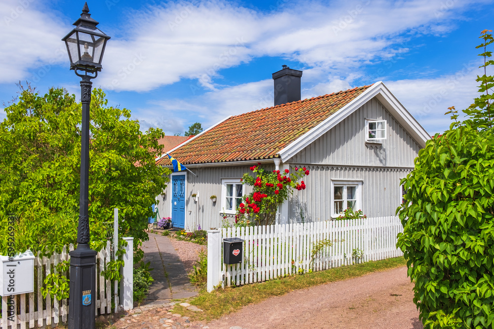 Sticker Idyllic little cottage with red roses in an alley