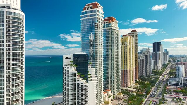 High view of Sunny Isles Beach city with heavy urban traffic and expensive highrise hotels and condo buildings on Atlantic ocean shore. American tourism infrastructure in coastal southern Florida