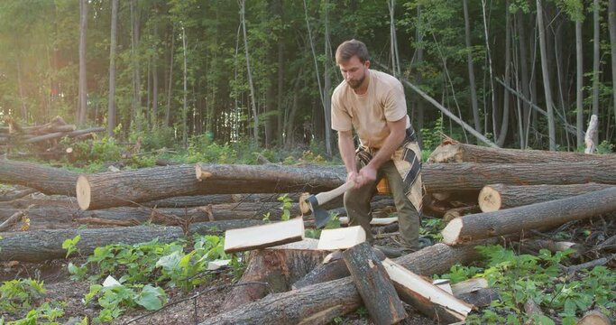 serious hardworking logger holding axe cutting a wooden stick Slow motion Muscular lumberjack during chopping process
