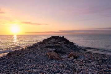 Obraz premium Breakwater on the rocky beach at sunrise