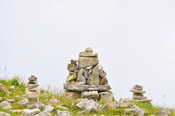 Pyramids of stones in a clearing on a mountain slope against a gray sky