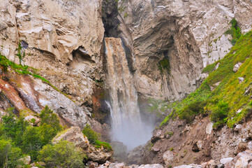 Big beautiful waterfall in the mountains among the rocks and large boulders