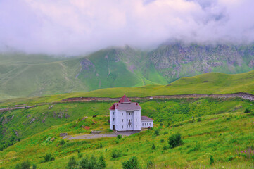 One beautiful house and a domestic horse in a clearing against the backdrop of mountains and hills