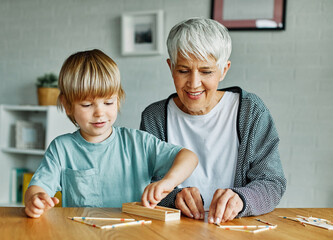 grandchild family child grandparent grandmother game playing boy stick pick up board board game...