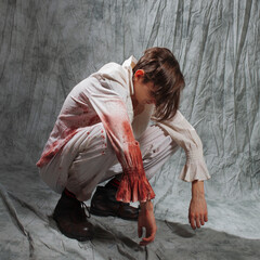 A crazy killer in bloodstained pajamas squats, an image for horror movies