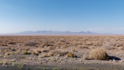 An empty desert area with mountains in the background