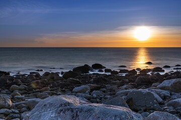 Fototapeta na wymiar there is some rocks near the ocean as a sun sets