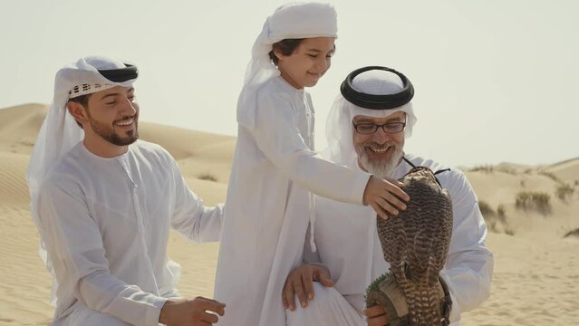 Three generation family spending time in the desert with the falcon bird making a safari in Dubai. Concept about middle eastern cultures and lifestyle in the emirates