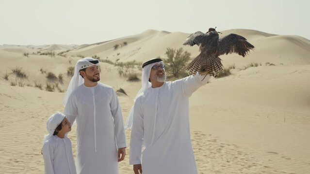 Three generation family spending time in the desert with the falcon bird making a safari in Dubai. Concept about middle eastern cultures and lifestyle in the emirates