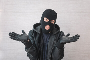 Young handsome man wearing burglar mask clueless and confused with open arms, no idea concept. thief apologizes. justification for arrest - obrazy, fototapety, plakaty