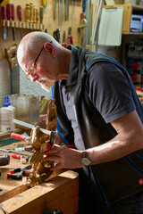 Craftsman carving a piece of wood to make a golden frame
