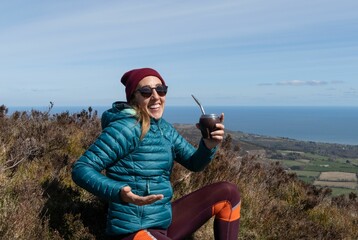 Young female hiker enjoying a Mate drink on the Glendalough Wicklow Mountains