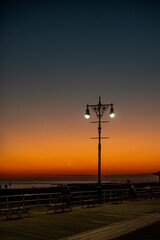 Beautiful shot of a bright orange blue sunset sky over lamp post silhouettes on Brighton Beach