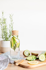 Infused  water with cucumber, lemon and thyme in glass bottle on wooden table. Diet, detox, healthy eating, weight loss concept