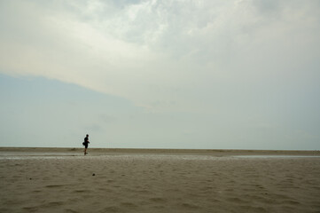 Fototapeta na wymiar landscape of Bakkhali sea shore. Silhouette of a man running on the beach at sunset. 