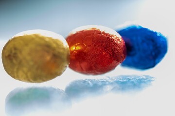 Colorful chocolate Easter eggs sitting in a row on a white background