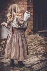 Fototapeta na wymiar Little girl wearing an old-fashioned brown dress.