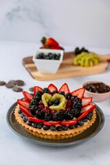 Delicious fruit tart with ingredients on a marble table
