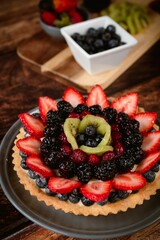 Delicious fruit tart with ingredients on a wooden table