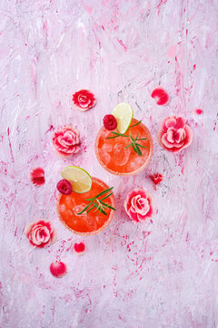 Klassischer Rosa Daiquiri mit Rum, Orangen Lik&ouml;r und Limetten Saft serviert als Valentinstag Geschenk in zwei Gl&auml;sern und dekoriert mit Rosen und Himbeeren
