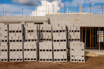 Stacks of hollow concrete blocks in front of single-family house under construction in a suburban development on a sunny afternoon in southwest Florida