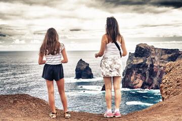 Woman and her daughter looking at the rocks above the sea from Miradouro de Sao Lourenco in Madeira...