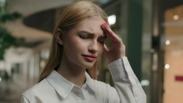 Caucasian woman sick girl in shopping mall close-up portrait stressed unhealthy businesswoman touching head rubbing temples covid19 symptom suffer from migraine pain difficult decision health problem