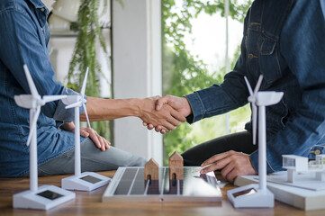 Engineers and developers of renewable energy systems go hand in hand. with solar panels and a model house on the table. To design use of renewable energy with wind and solar energy.