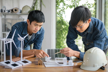 Close-up at model house, Engineers pointing at model house with their hands. To jointly design the use of renewable energy with wind and solar energy. Concept of using renewable energy.