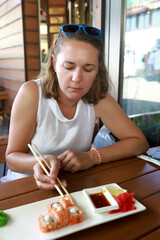 Woman eating sushi with chopsticks