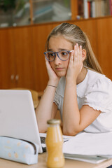teenage girl student in glasses working at laptop in classroom, shocked emotional face