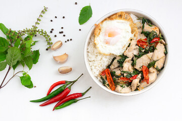 Stir fried basil with chicken and fried egg has rice in bowl on white table top view.