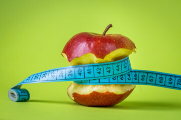 Weight loss concept, Bitten apple related by tailor meter, positive green background, Healthy and tasty, positive approach to diet