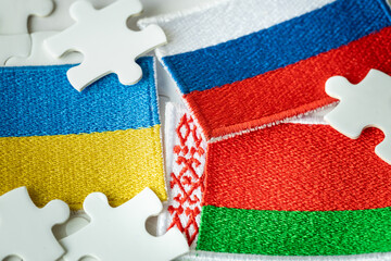 The flag of Belarus and the background of the flags of Russia and Ukraine among the jigsaw puzzles,...