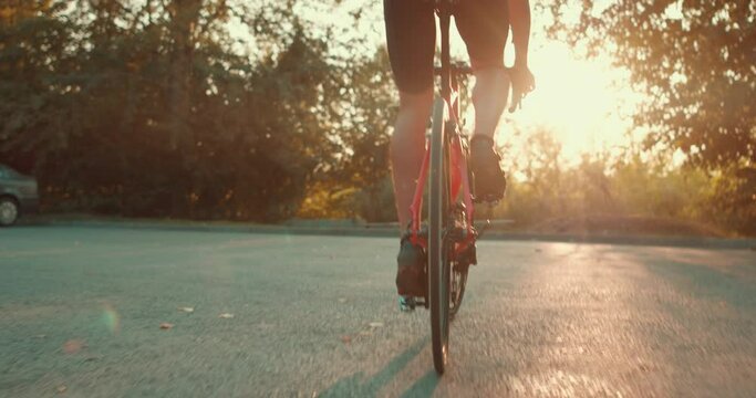 A man is riding a bike on road The camera is following him from behind. He is wearing cycling gear. lifestyle health and body care slow motion