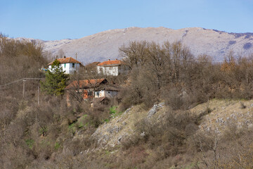 Malo Bonjince, Serbia - February 19. 2023 A small group of houses on a hill with a large, dry mountain in the background in the village of Malo Bonjince on a sunny early spring day
