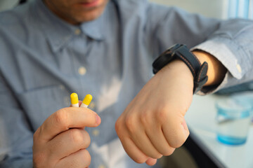 alarm clock pills. Hand of man taking pill. Healthcare and medicine concept. taking pills on a...