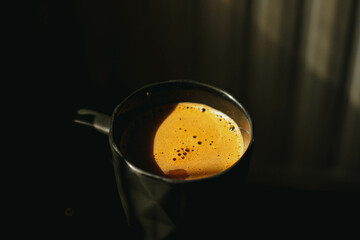 A black cup of coffee next to the sunlight. It's nice for a background with the shadows cast by the sun.